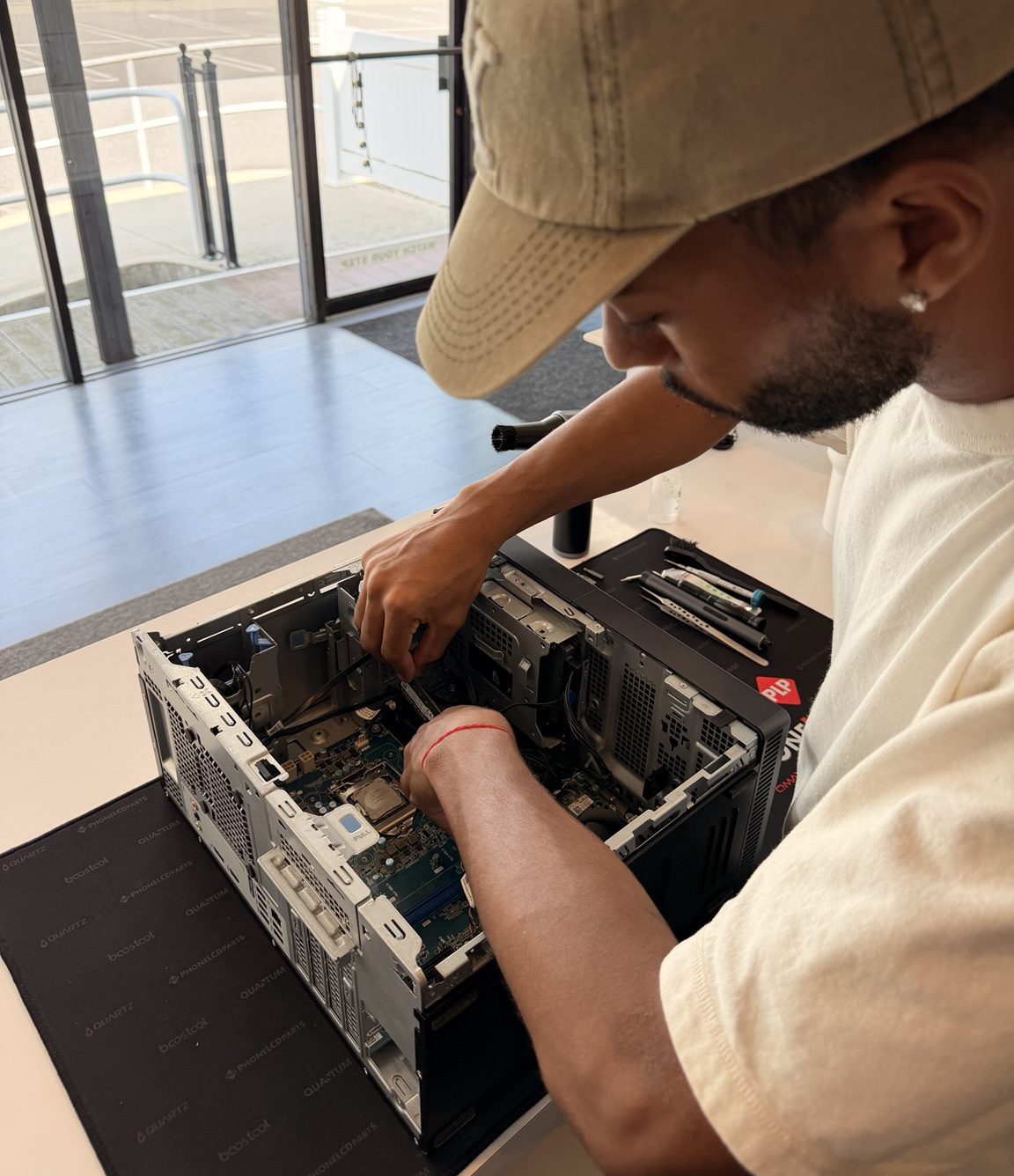 Benjamin working inside an opened desktop computer at the repair bench, with tools laid out on the mat.