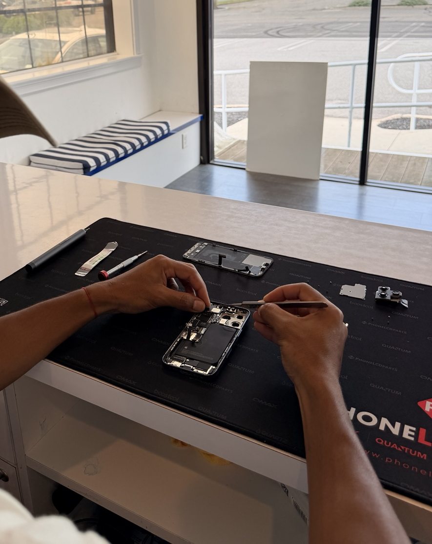 A smartphone opened on the repair bench with its internal components exposed during a repair.